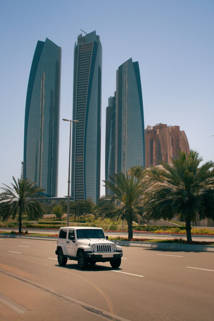 Modern high-rise residential skyscrapers and palm trees along a street, showcasing local coverage areas for apartment movers Abu Dhabi.