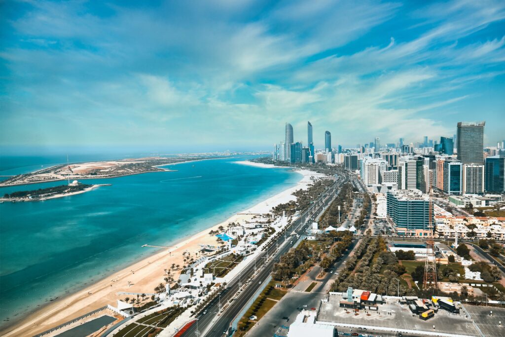 Panoramic high-angle view of coastal city buildings, clear blue waters, and surrounding urban roads, highlighting service zones for movers and packers MBZ City.