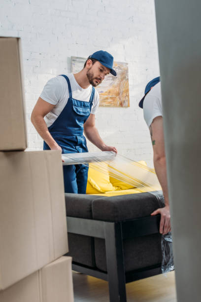Professional relocator wrapping a sofa in stretch film to demonstrate expert packing and unpacking services Abu Dhabi.