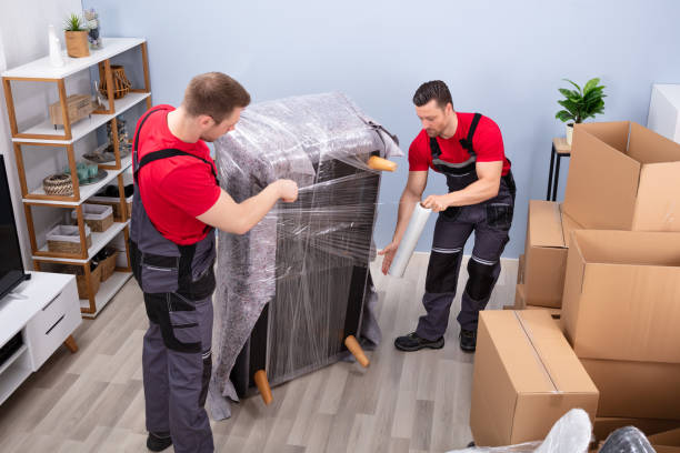 Professional team members wrapping furniture securely in plastic stretch film next to moving boxes, demonstrating reliable services from movers and packers Reem Island