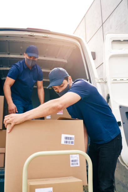 Professional relocators carefully organizing cardboard boxes inside a transport truck, demonstrating the efficiency of studio movers Abu Dhabi.