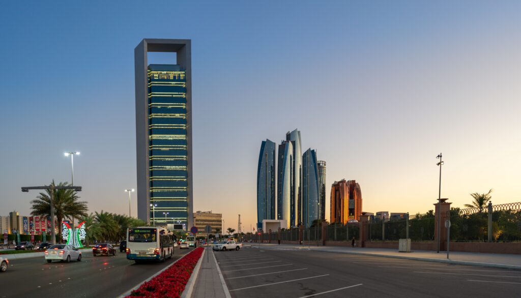 Evening view of modern skyscrapers, city roads, and a public bus along a major highway, highlighting coverage zones for movers and packers Airport Road.