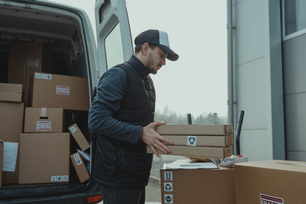 Professional house movers Abu Dhabi loading flat-packed cardboard boxes into the back of a moving van.