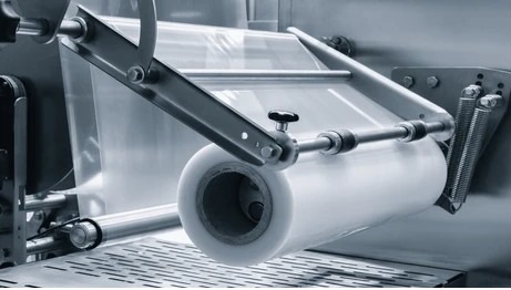 Roll of clear plastic stretch film packing material mounted on packaging machinery