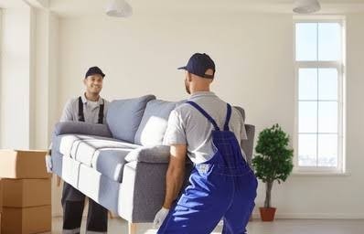 Two professional movers carefully carrying a couch during high-rise apartment relocation.