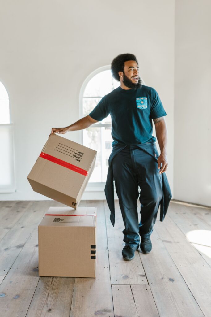A removal specialist carefully lifting a heavy box in a bright room, highlighting the professional handling required by piano movers Abu Dhabi.