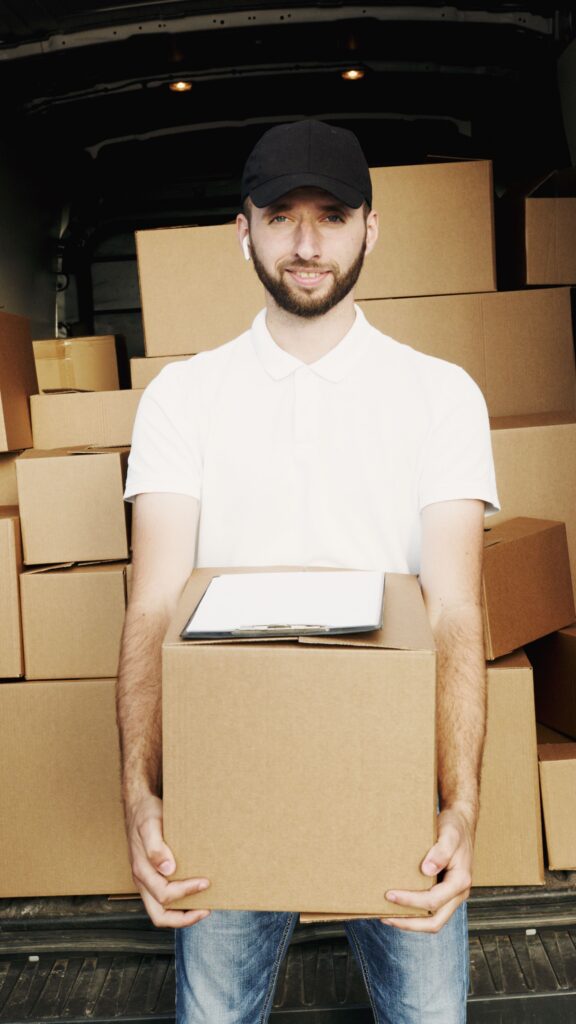 A professional transport specialist standing in front of loaded cargo inside a delivery truck, showcasing secure logistics by heavy item movers Abu Dhabi.
