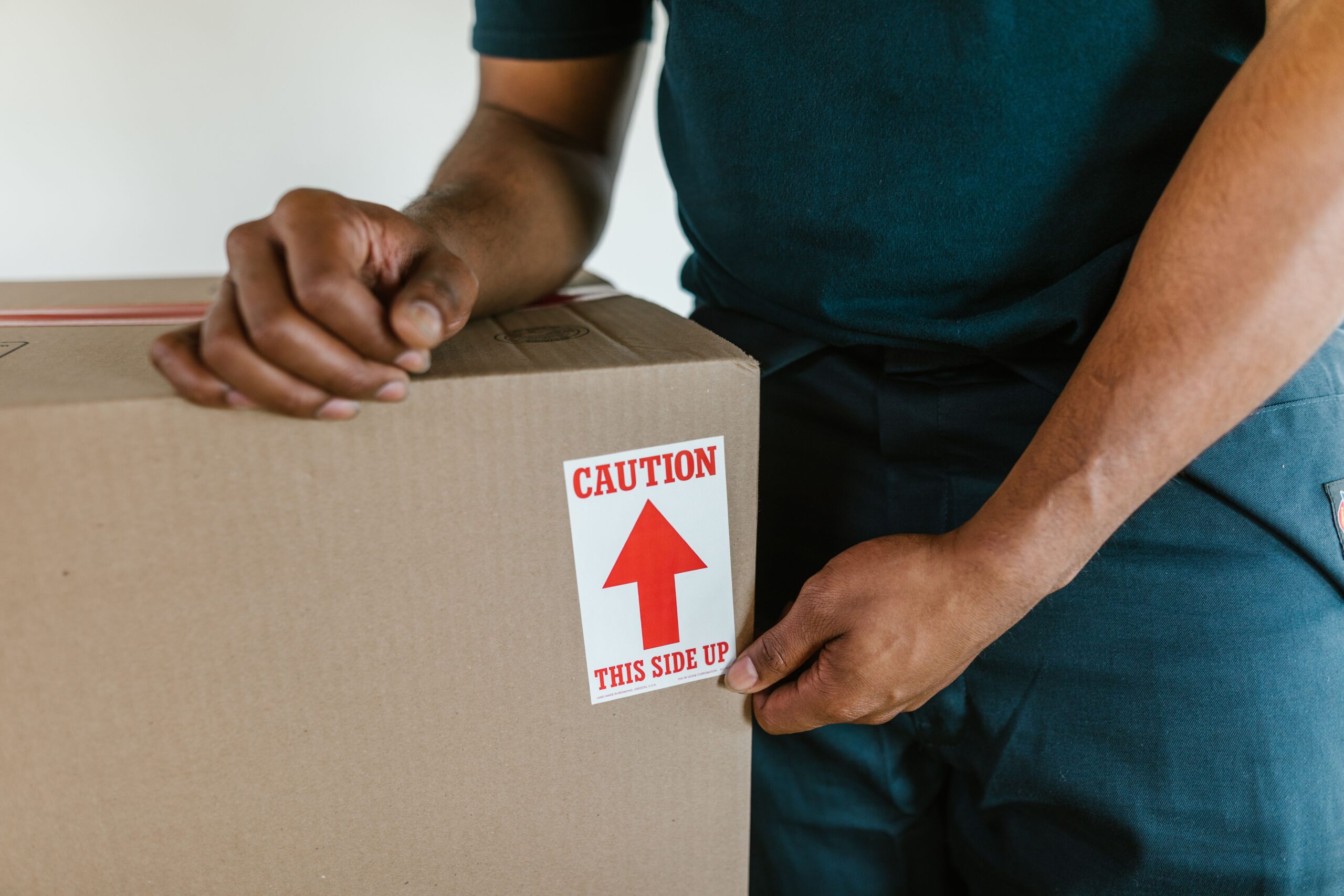 House movers Abu Dhabi sealing a fragile cardboard box for single item or partial load shipping.