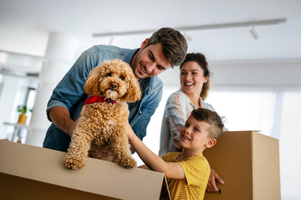 Happy family with a child and small dog unpacking moving boxes in an Abu Dhabi villa.